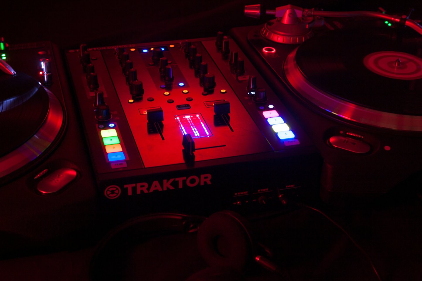 A professional DJ mixer and turntables sit on a table.