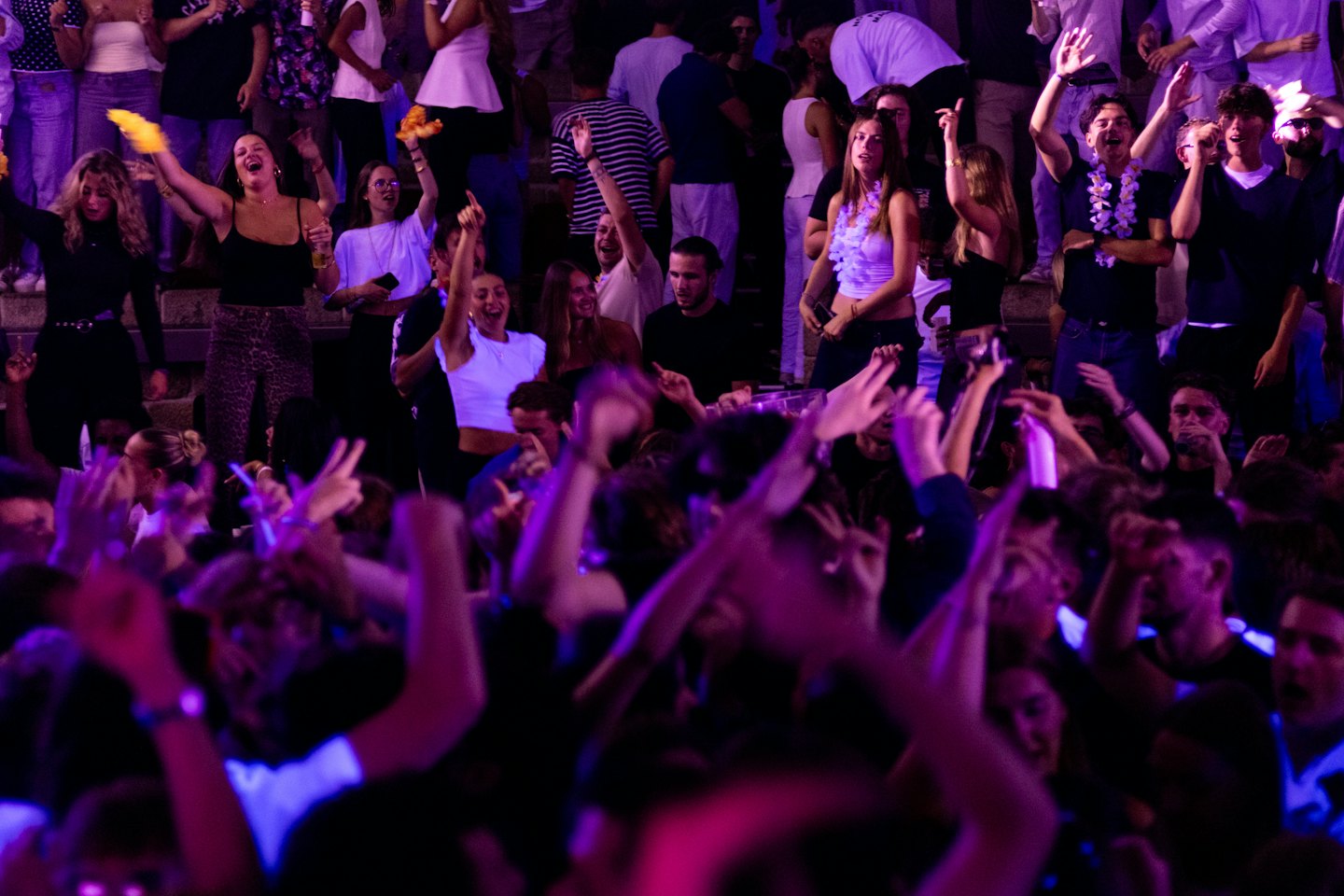 A group of friends dance with hands raised at a party.